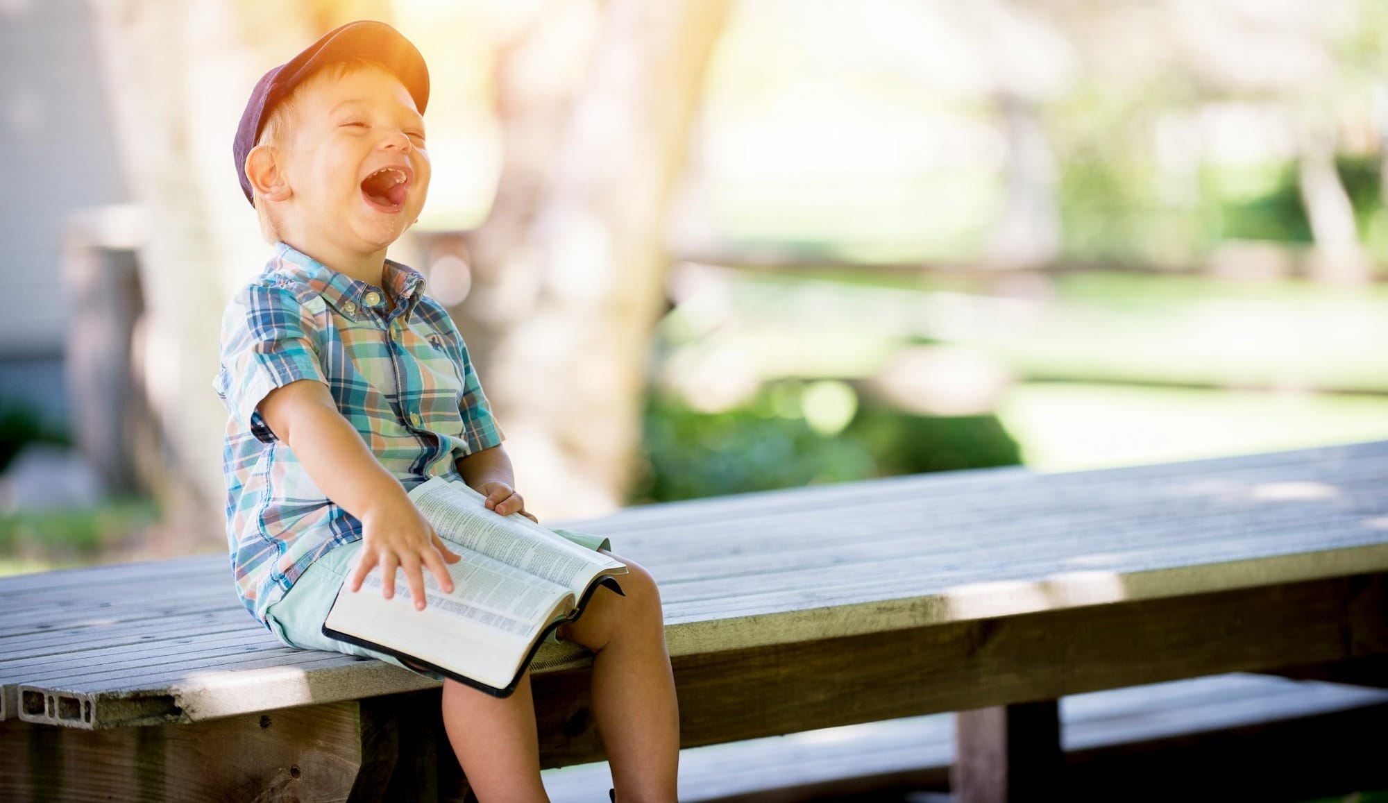 boy sitting on bench while holding a book