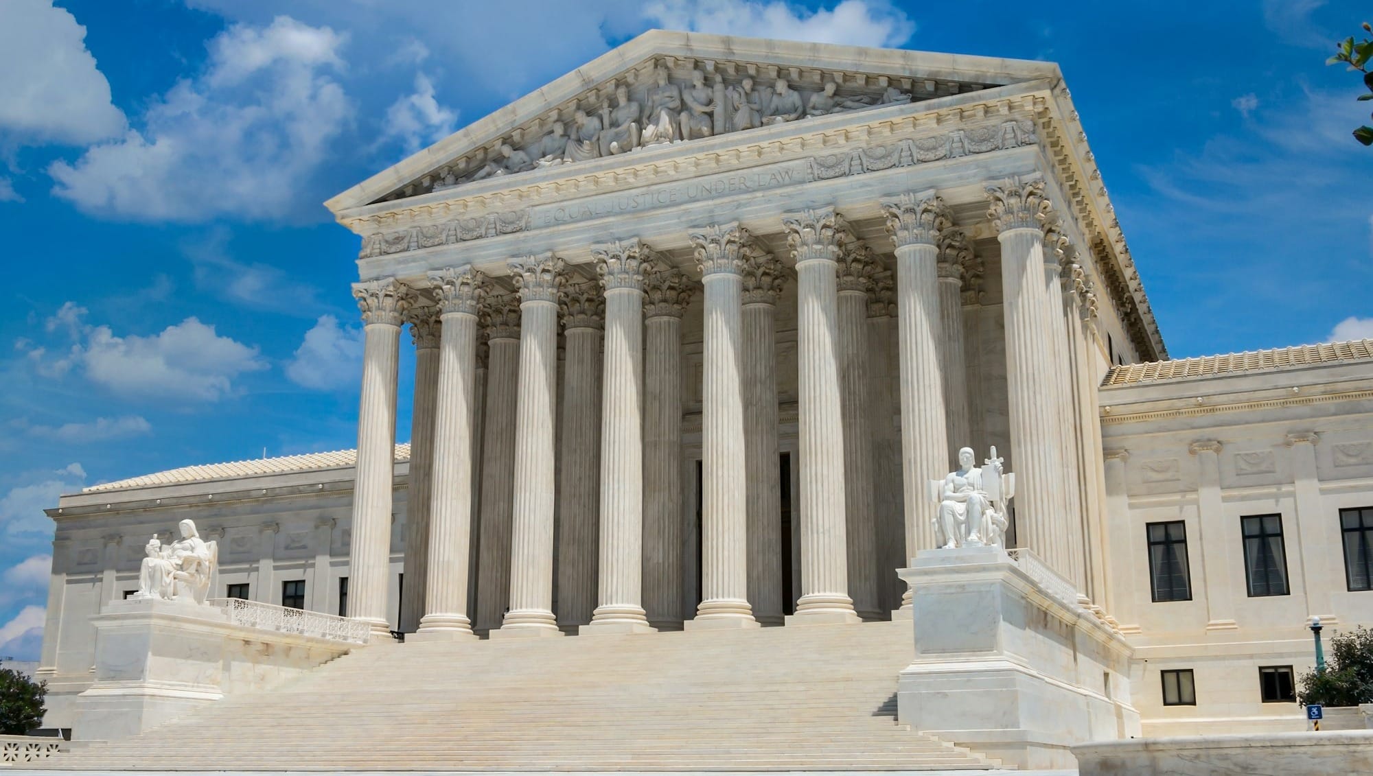 a large white building with columns with United States Supreme Court Building in the background