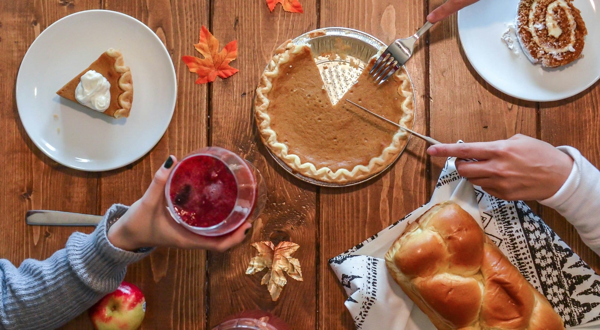 person slicing pie beside bread