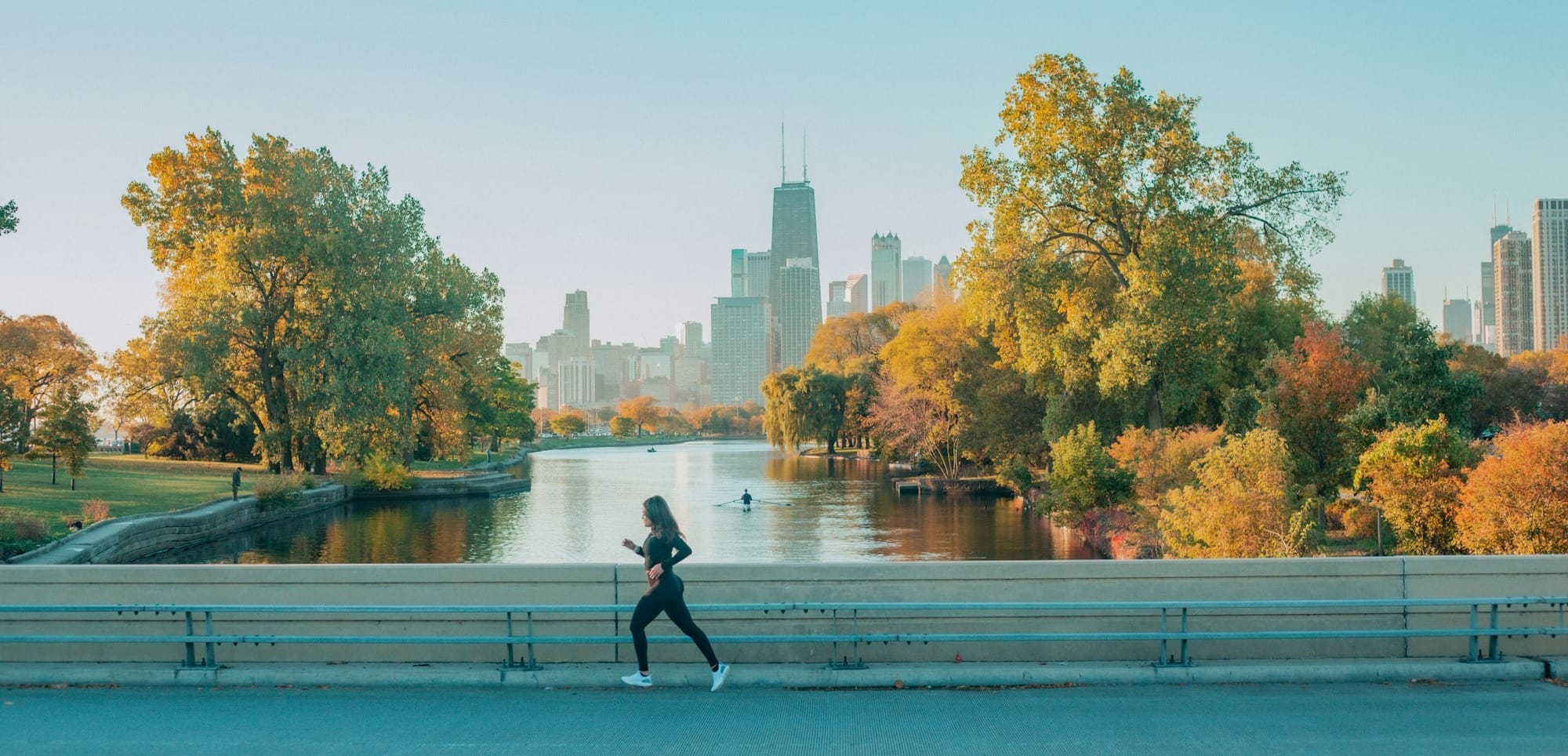 a woman running down a street next to a river