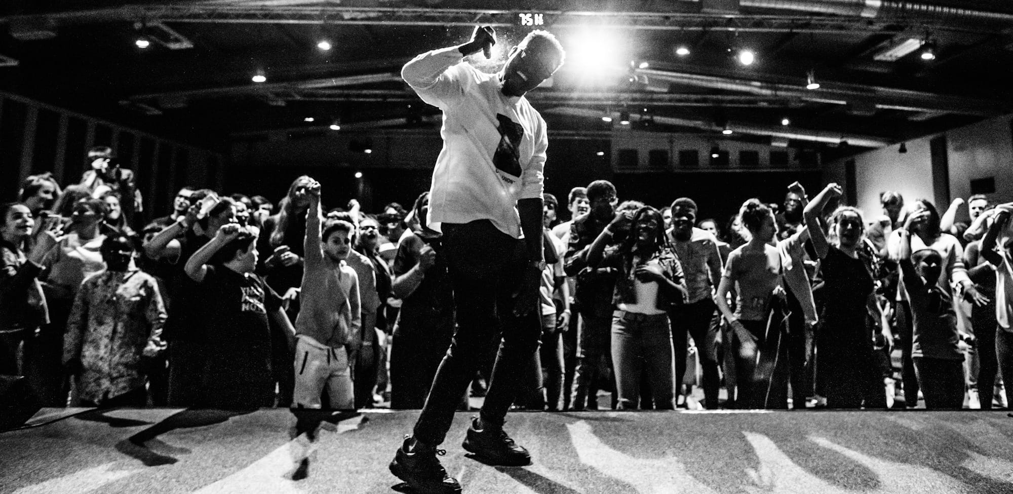 man in white t-shirt and black pants singing on stage